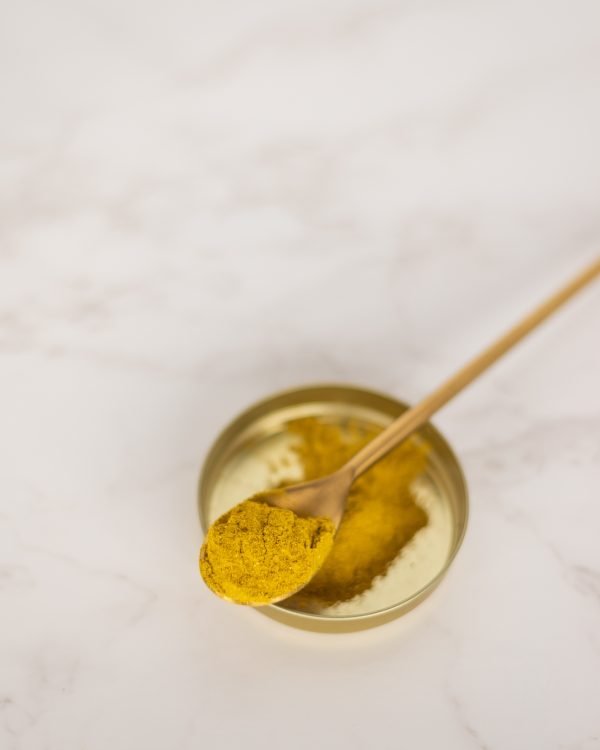 A gold teaspoon with turmeric powder