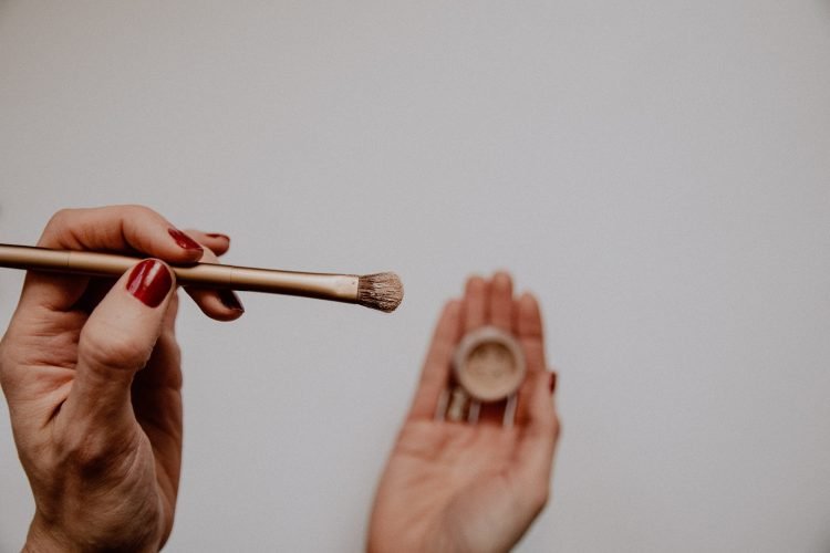 Hand holding an eyeshadow brush with shadow on it