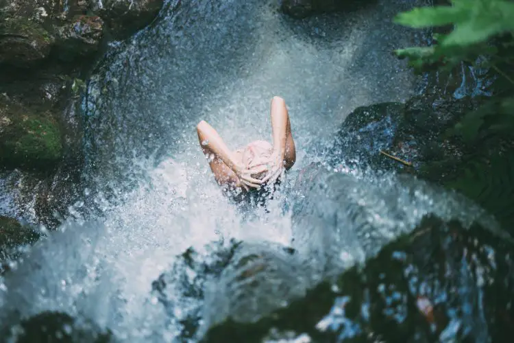 woman bathing under natural water
